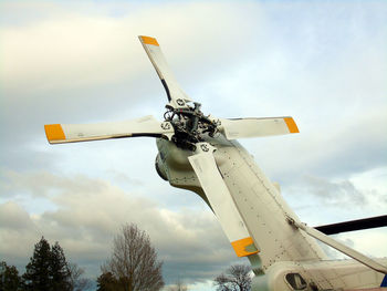 Low angle view of helicopter propeller against cloudy sky