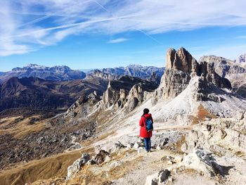 Rear view of woman standing on rocky mountains against sky