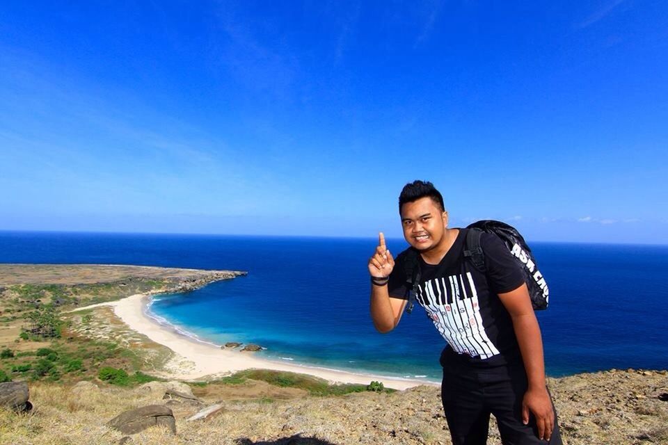 sea, beach, horizon over water, lifestyles, blue, shore, leisure activity, casual clothing, water, person, copy space, young adult, clear sky, vacations, sand, standing, young men, portrait