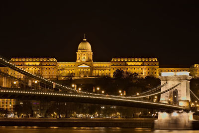 Illuminated bridge over river at night