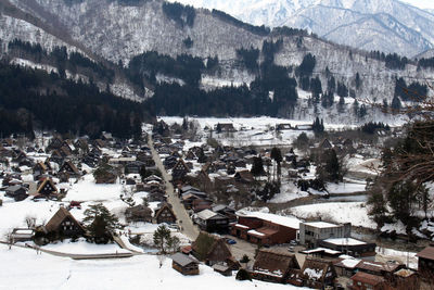 High angle view of townscape by snow covered mountain