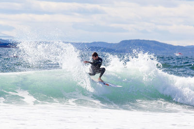 Man surfing in sea against sky