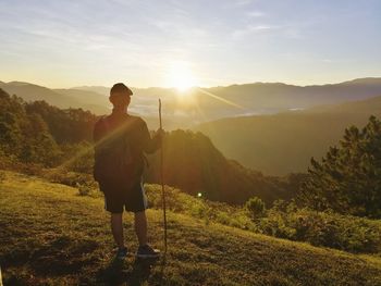 Man standing on mountain against sky during sunset