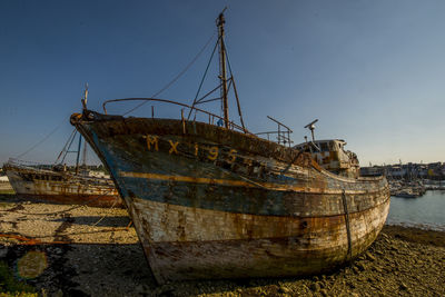 Abandoned boat moored at sea against sky