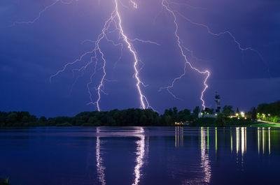 Firework display over lake against sky at night