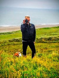 Man standing on grassy field against sky