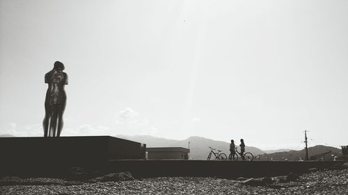 Sculpture of man and woman on seashore against sky