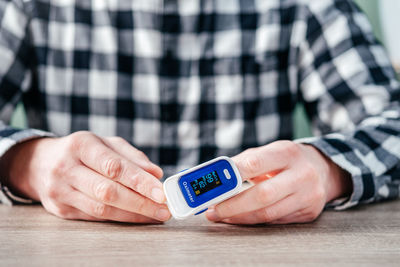 A man checking oxygen level at home with home oximeter, patient measuring the blood oxygen with