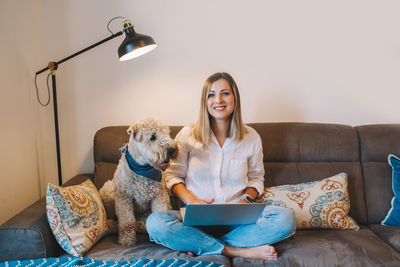  woman sitting on couch in living room with laptop surfing internet. woman freelancer at workplace.