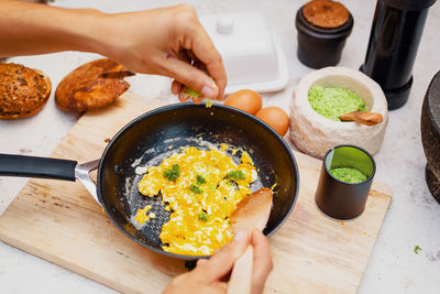 Scrambled eggs in a pan are seasoned with natural herb salt