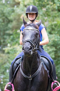 Smiling woman riding horse at forest