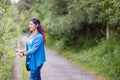 Portrait of young woman standing on road