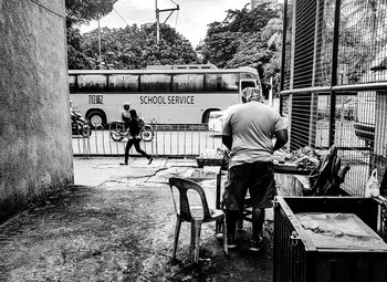 Rear view of man standing on bicycle in city