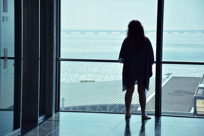 Rear view of woman looking through window