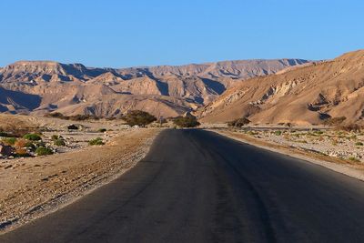 Empty road in desert against clear blue sky