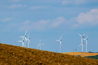 Windmills on field against sky