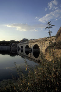 Arch bridge over river against sky