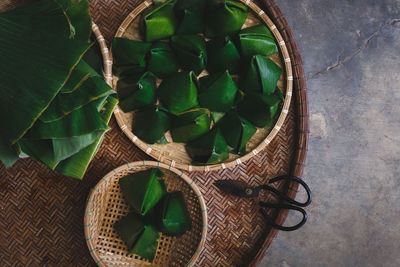 Directly above view of rice cakes wrapped in banana leaves on bamboo tray