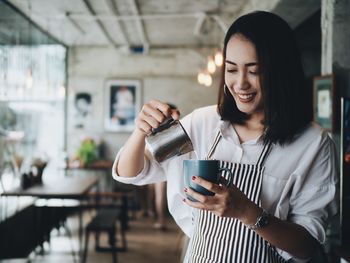 Young woman making coffee on counter at cafe