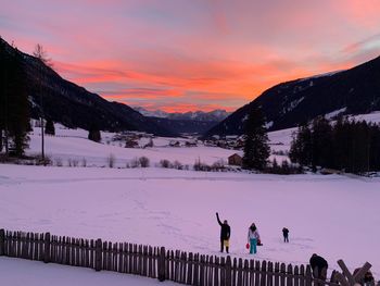 People on snow covered mountain against sky during sunset