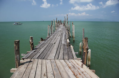 Wooden pier over sea against sky