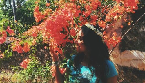 Close-up of smiling young woman smelling flowers while standing at park