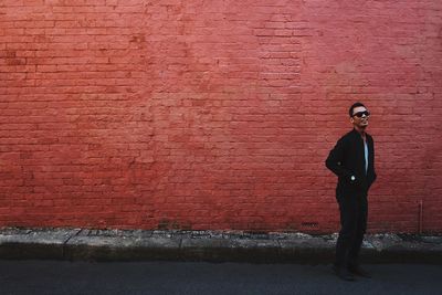 Full length of woman sitting on brick wall