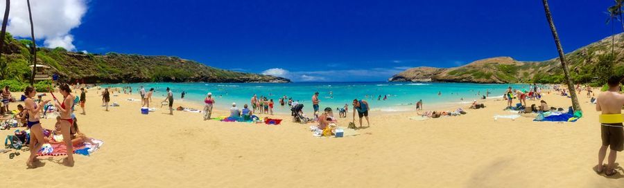 Group of people on beach against blue sky