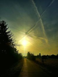 Road amidst trees against sky during sunset