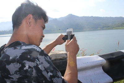 Young man using mobile phone against mountains