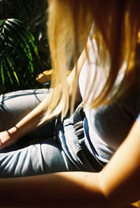 Midsection of woman sitting on chair by plant