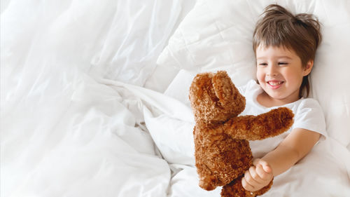 Girl with teddy bear on bed