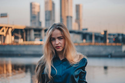 Portrait of beautiful woman against river in city