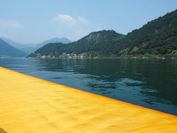 Scenic view of lake by mountains against sky