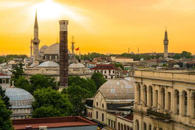 Buildings in city against sky during sunset