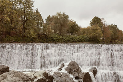 Scenic view of waterfall in forest against sky