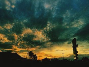 Low angle view of silhouette trees against dramatic sky