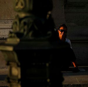 Smiling woman behind pole on street