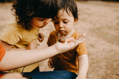 Brother and sister watching snail on mother's hand