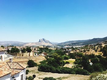 Houses by mountains against clear blue sky