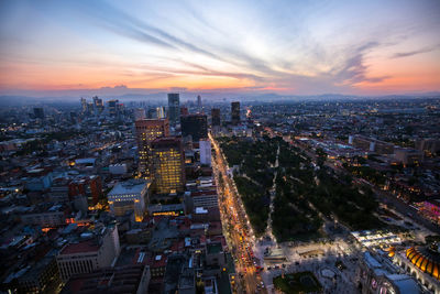 High angle view of illuminated city buildings against sky during sunset