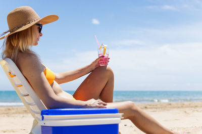 Rear view of young woman sitting at beach