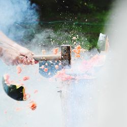 Cropped hand hammering watermelon on table 