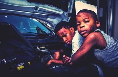 Portrait of boys repairing car at garage