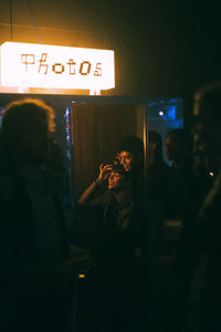 Young transgender woman with non-binary gender inside photo booth on weekend