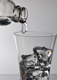 Close-up of drink pouring over water against white background