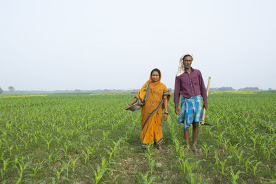 Rear view of people standing on field against clear sky