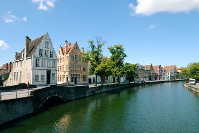 Buildings by river against sky in city