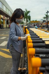 Rear view of woman with yellow umbrella standing in row