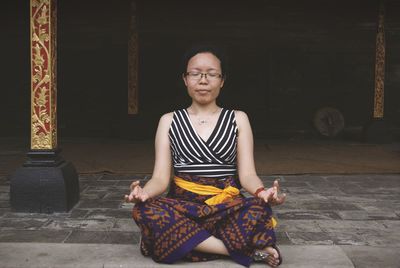 Mid adult woman meditating in lotus position at temple